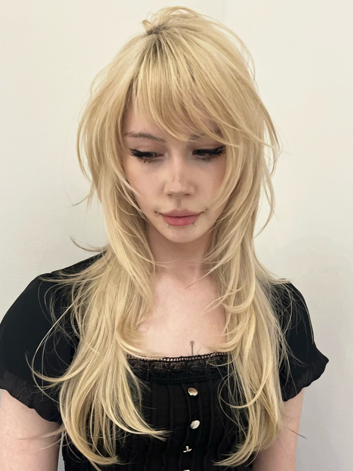 Woman with long blonde feathered layers and wispy sweeping bangs