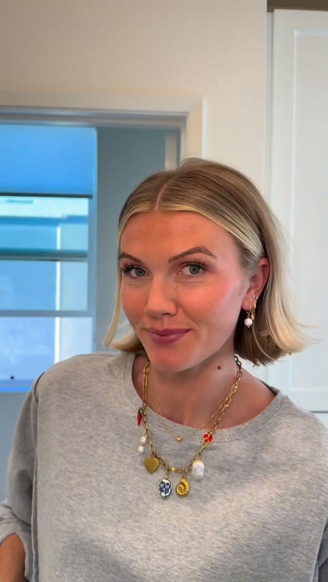 Woman wearing smooth, center-parted blonde hair tucked behind both ears