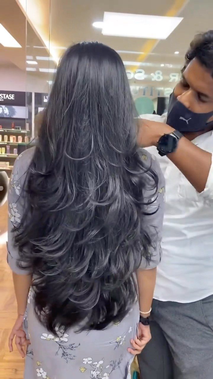 Long dark hair styled in loose layered waves by a salon stylist