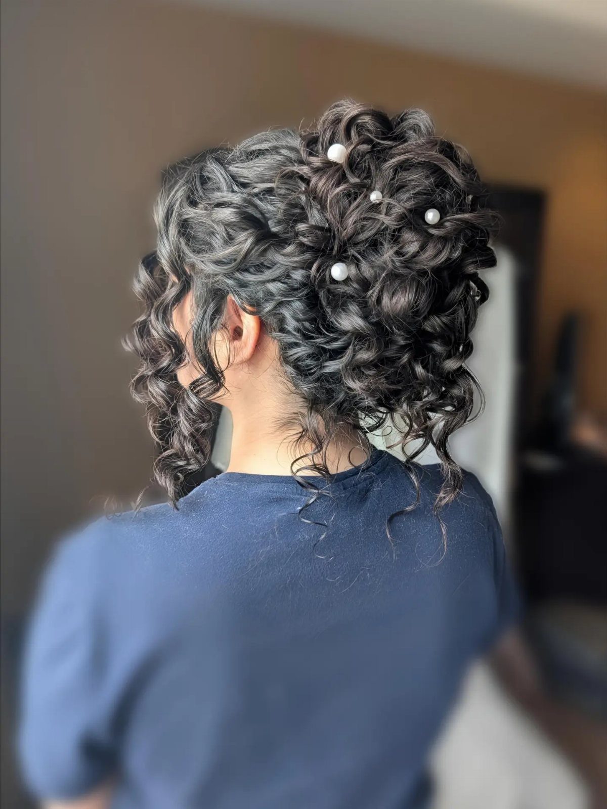 Curly updo with loose face-framing curls and pearl pins