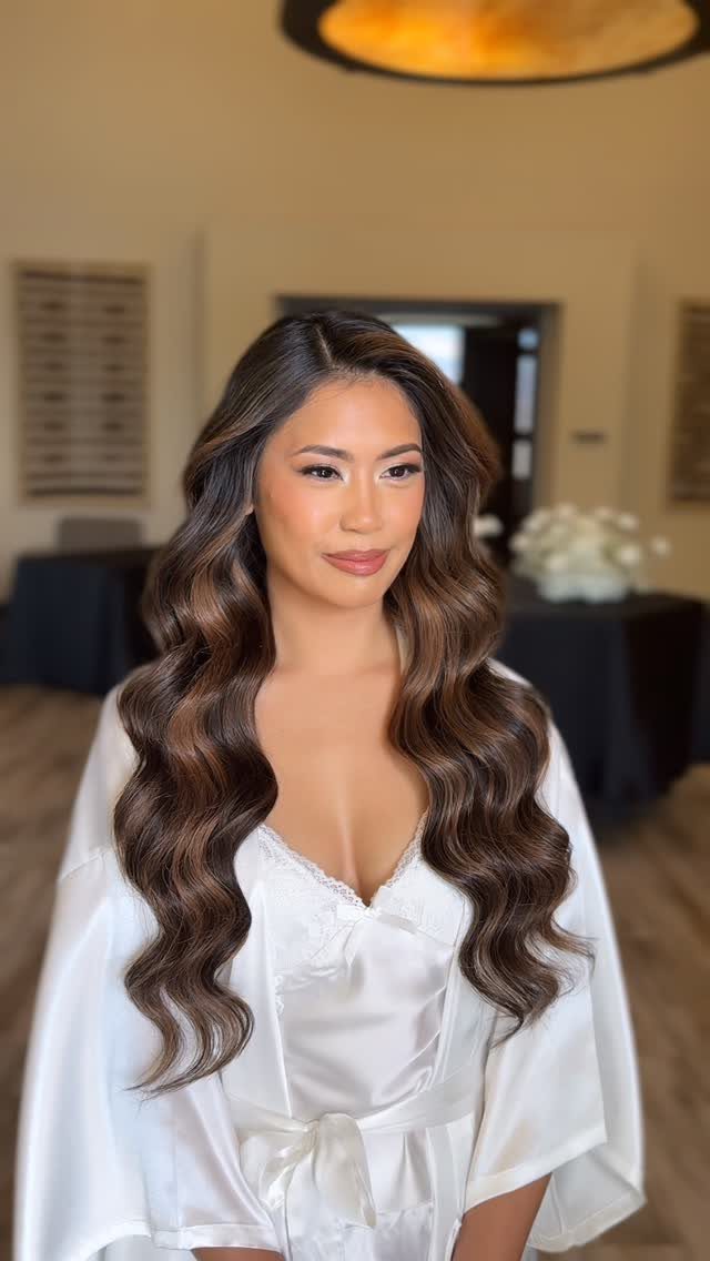 Woman with long brown hair styled in deep waves and a pronounced side part