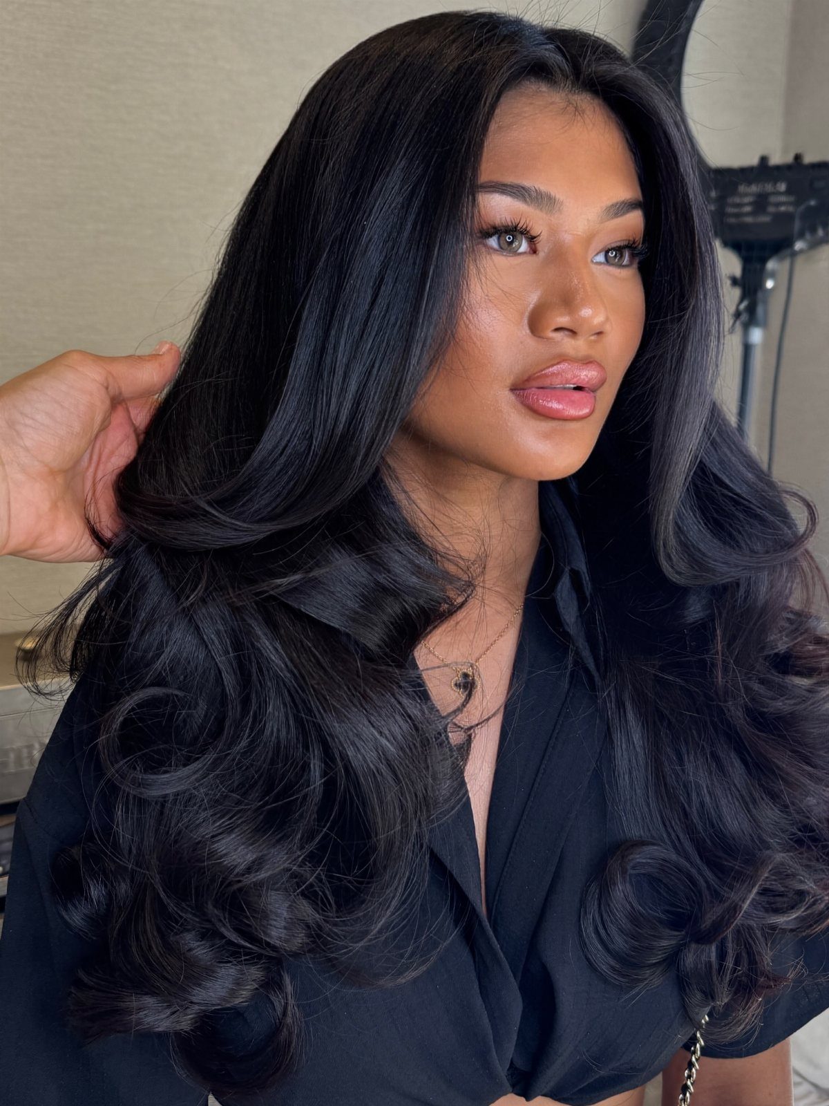 Long black hair styled in voluminous, glossy curls and bouncy waves