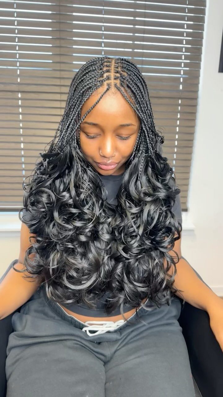 Woman with center-parted braids blending into long, voluminous black curls