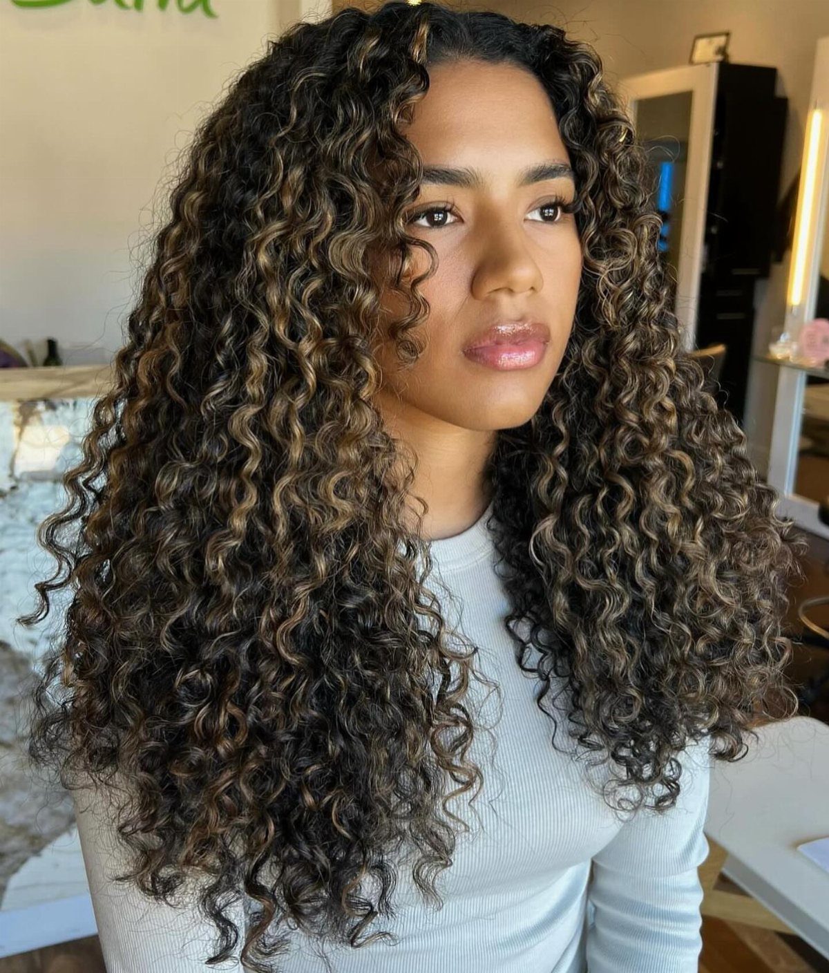 Woman wearing long, voluminous dark brown curls in a salon
