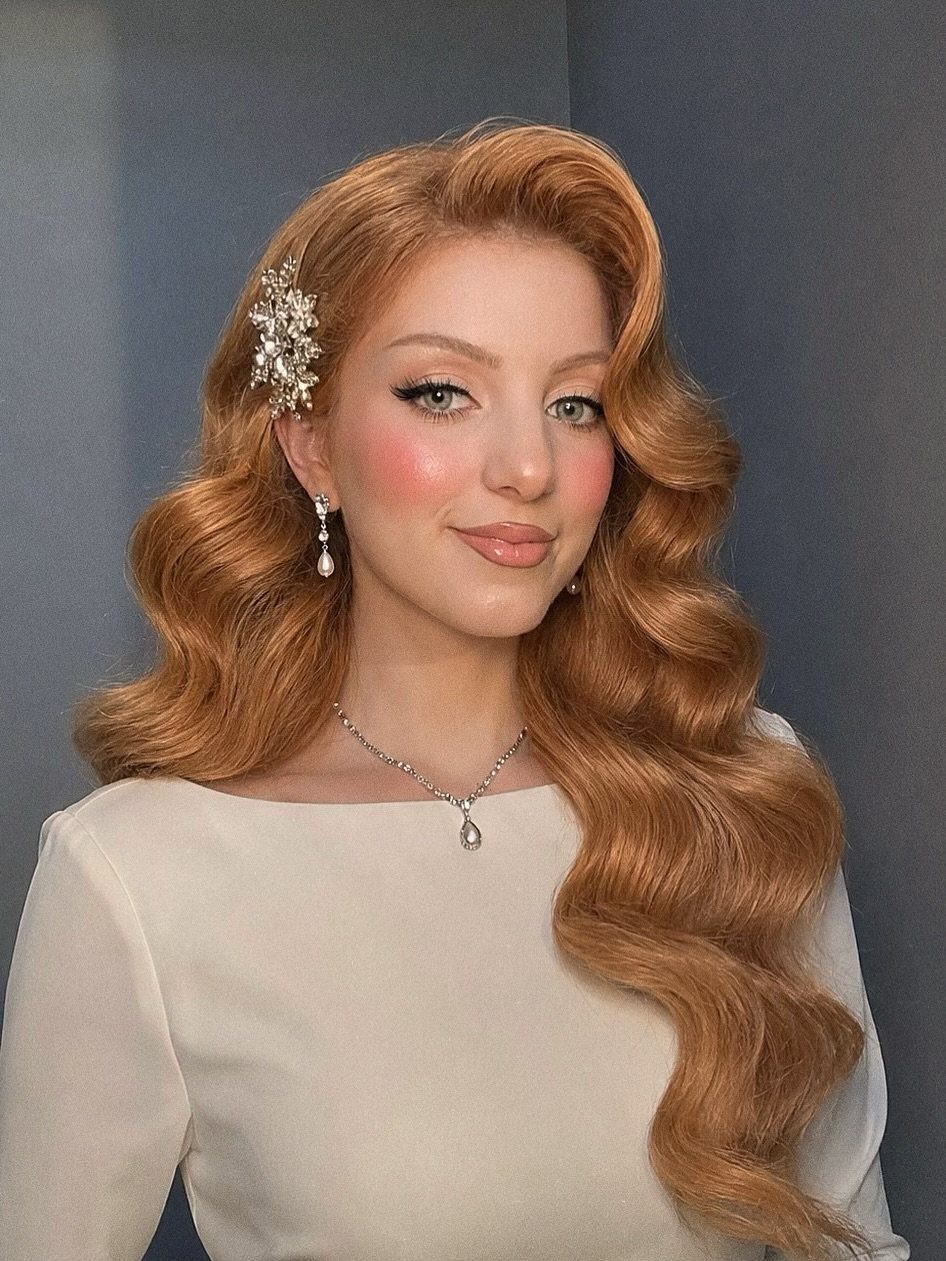 Woman with long copper hair styled in glossy Old Hollywood waves
