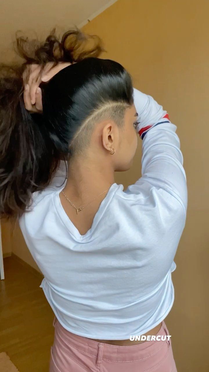 Long dark hair lifted to reveal a shaved undercut with a curved design