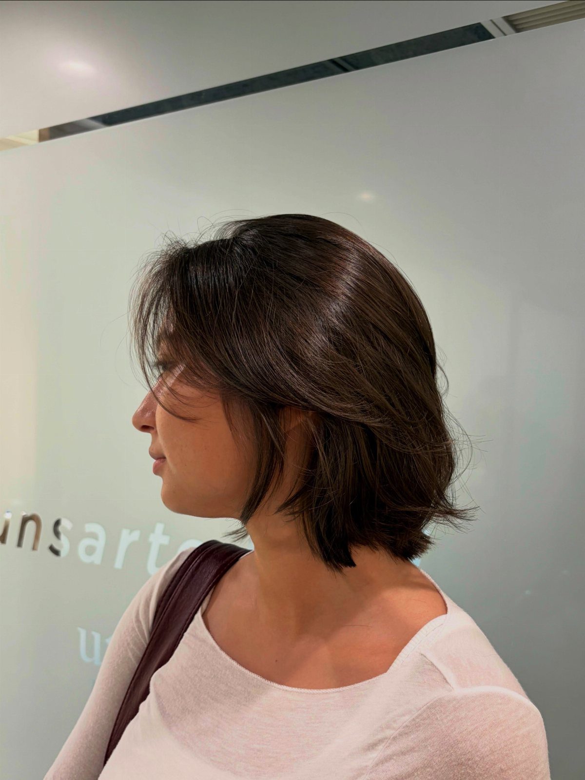 Woman showing a chin-length layered brown hairstyle with face-framing strands