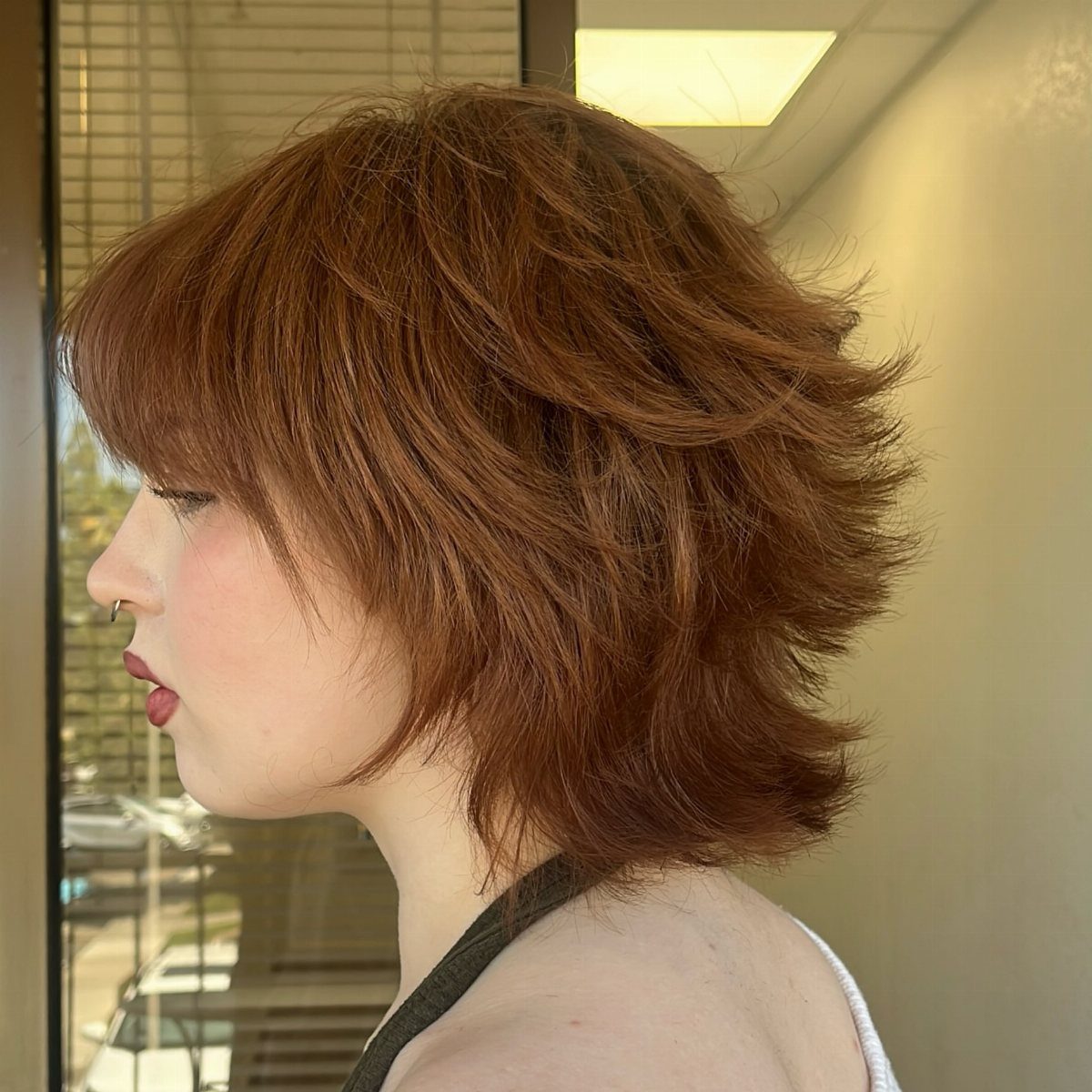 Edgy angled auburn bixie with choppy, spiky layers viewed from the side