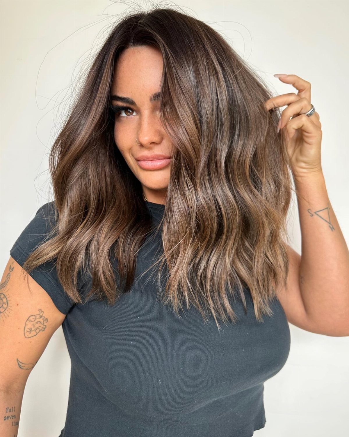 Woman with long highlighted brown waves wearing a dark gray top