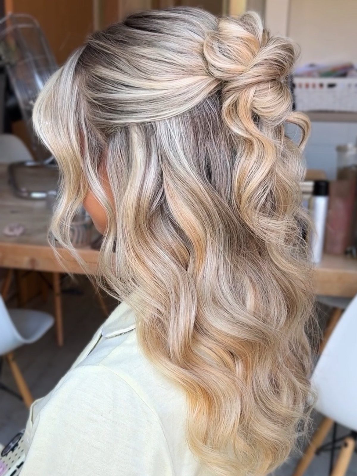 Blonde hair in a twisted half-up knot with long, loose waves