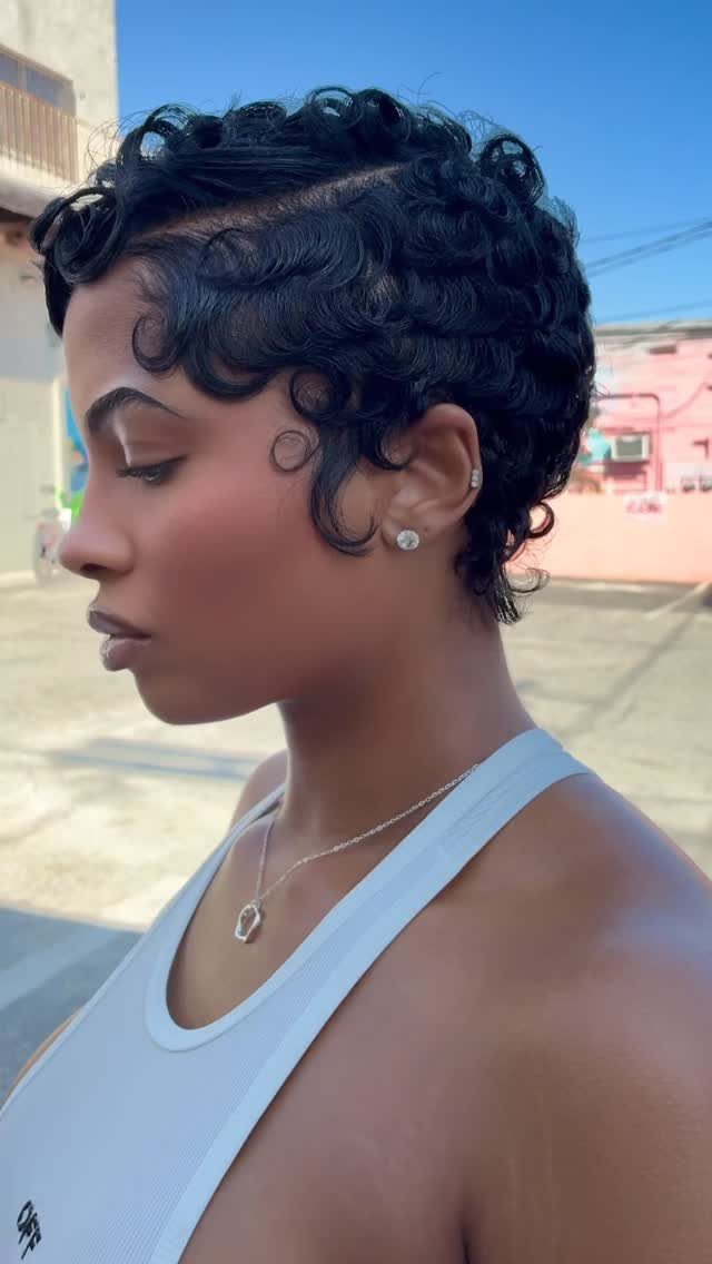 Woman with short black layered hair styled in sculpted curls and waves