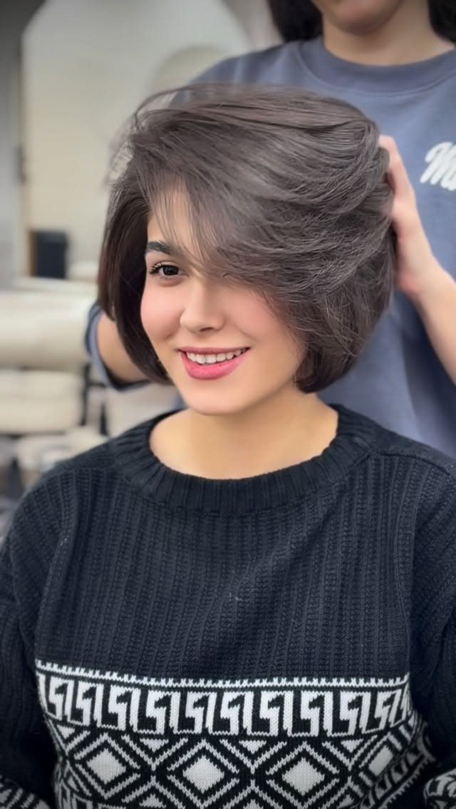 Woman showcasing short layered hair with swept bangs indoors