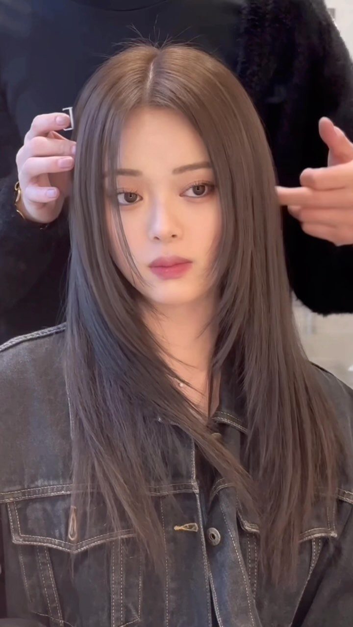 Long, sleek straight brown layers frame a woman’s face