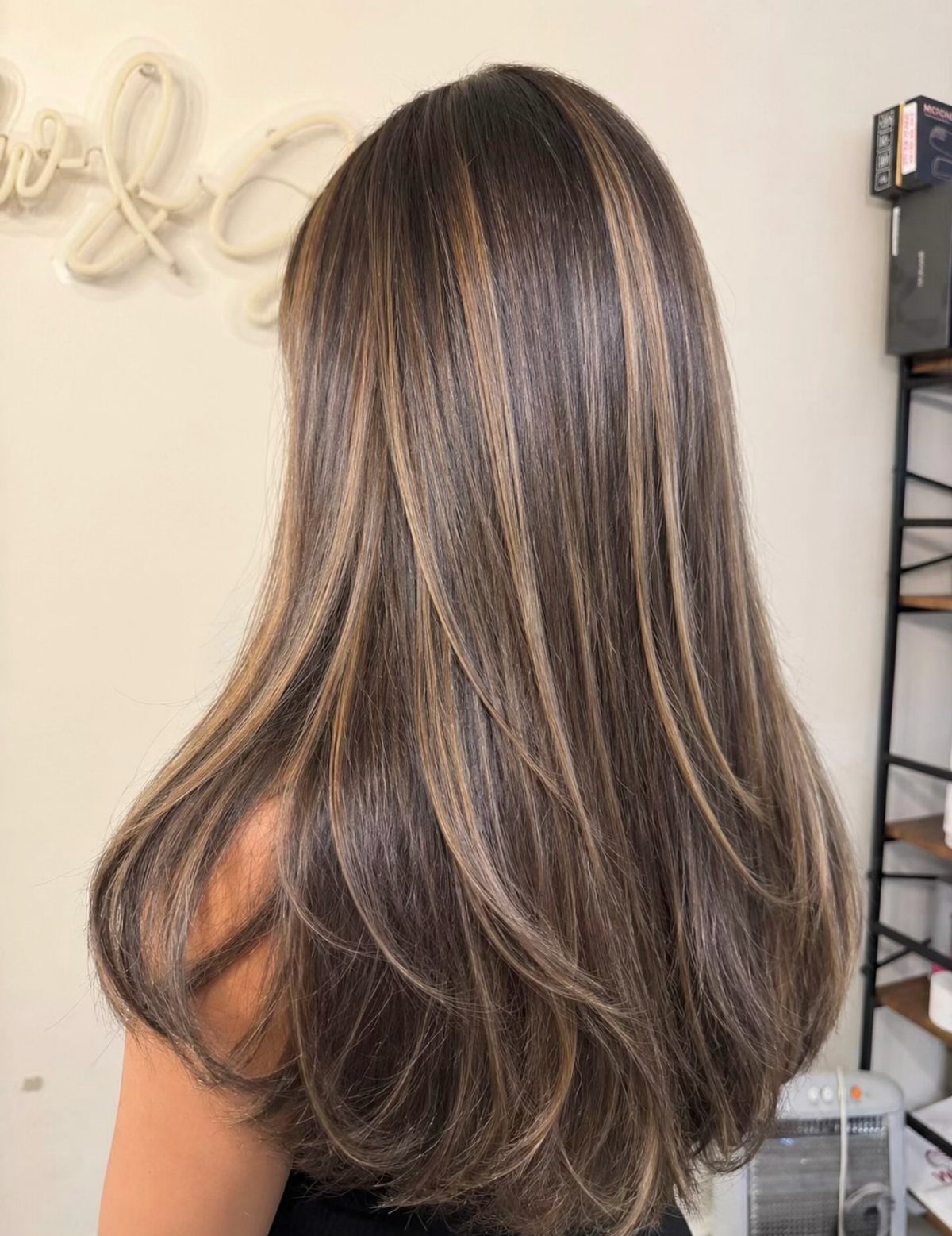 Shoulder-length brown hair with blended blonde highlights and softly curled ends