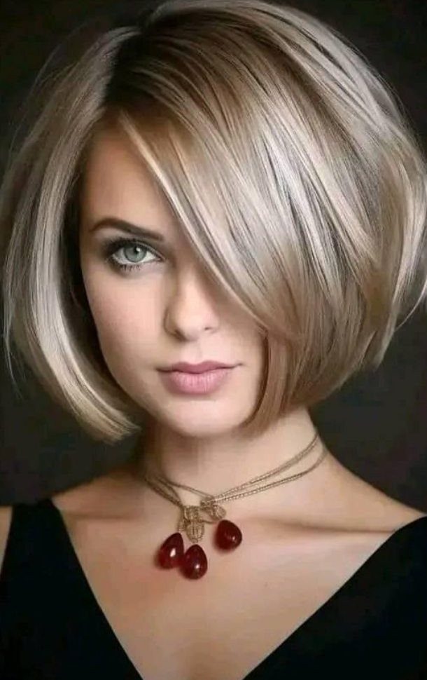 Woman with a polished blonde bob and deep side part, wearing layered necklaces.
