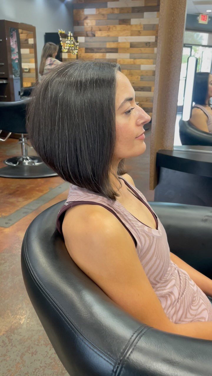 Woman in profile showing a sleek dark A-line lob in a salon chair