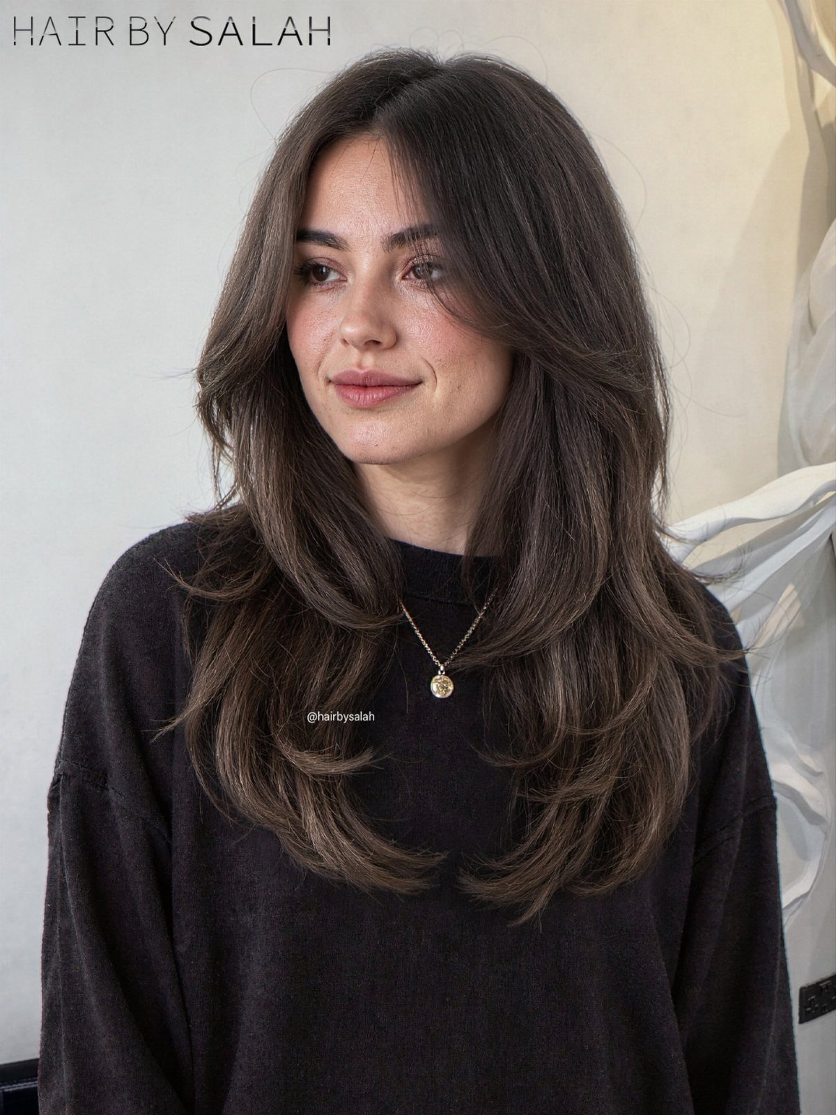 Long dark hair with center-parted curtain bangs and softly layered ends