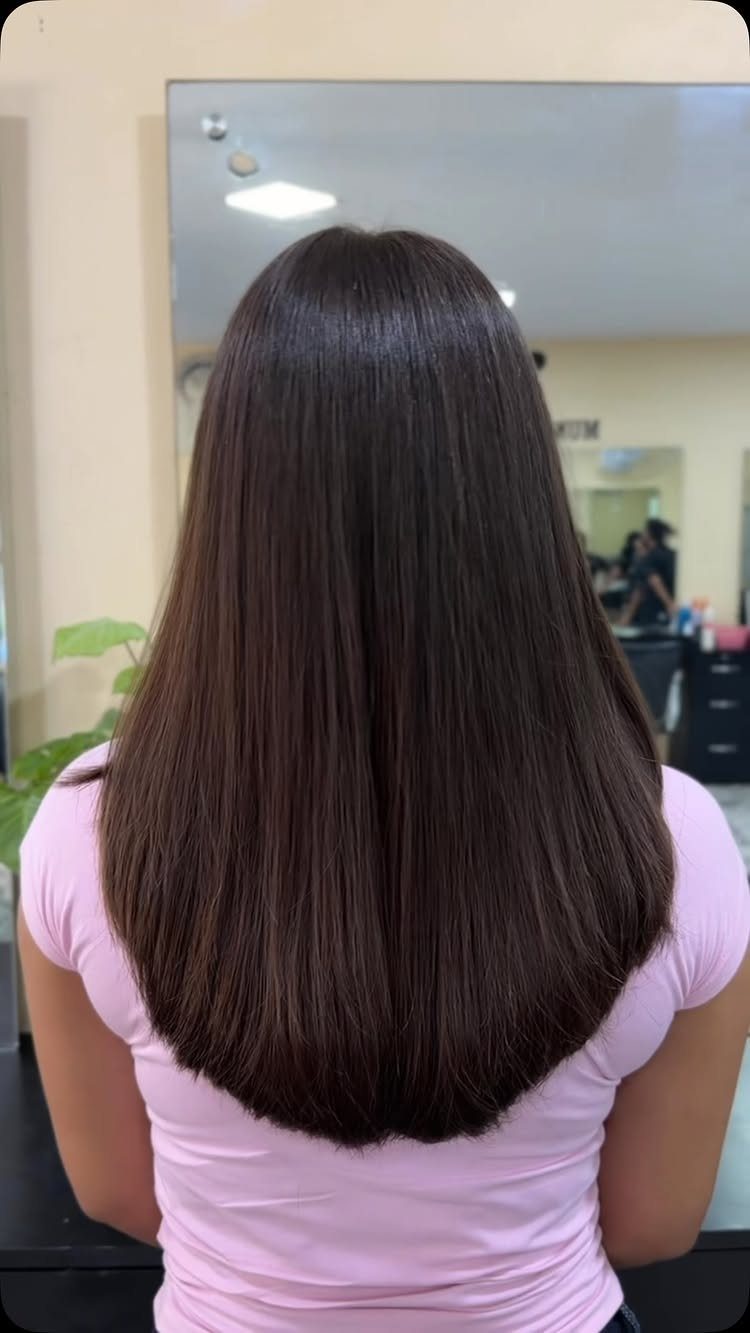 Long, smooth dark brown straight hair shown from behind in a salon