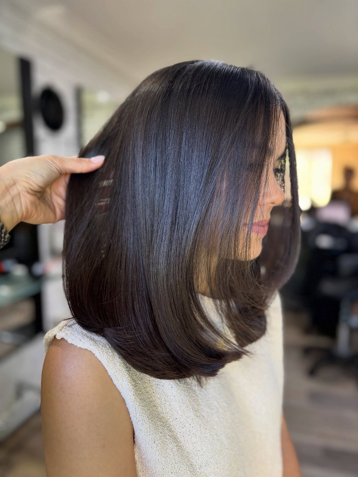 Shoulder-length straight brunette hairstyle with smooth layers and curved ends in a salon