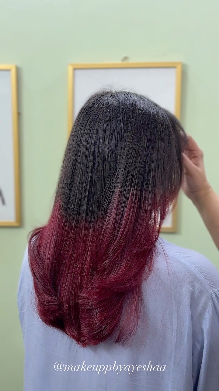 Long dark straight hair transitions into burgundy-red ends over a pale blue top