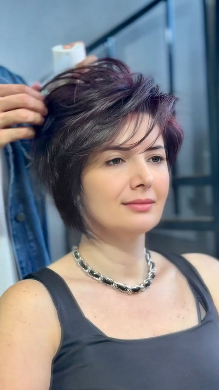 Woman with a textured, purple-highlighted pixie cut in a salon chair