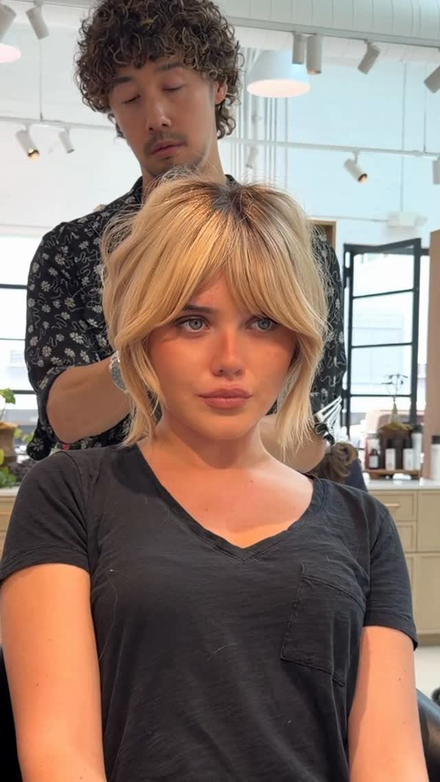 Woman with shoulder-length blonde layers and curtain bangs in a salon chair