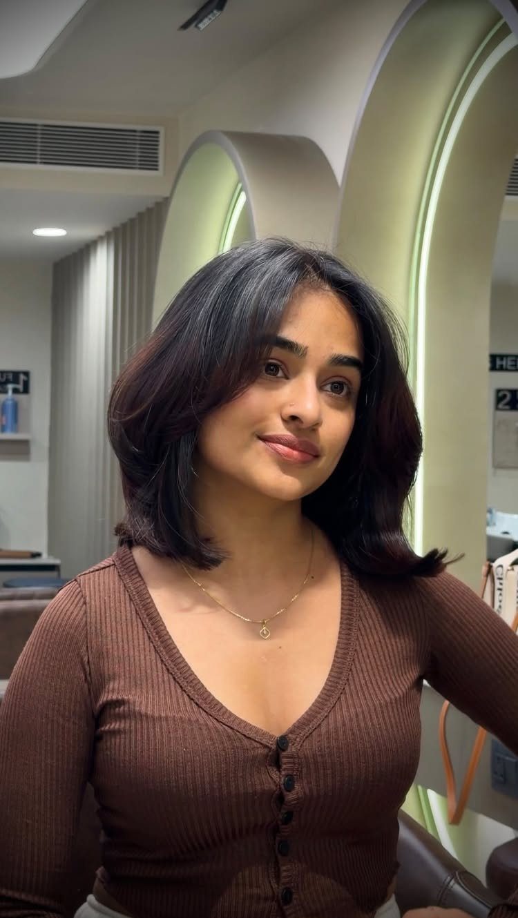 Woman showing a dark layered lob with softly curved shoulder-length ends