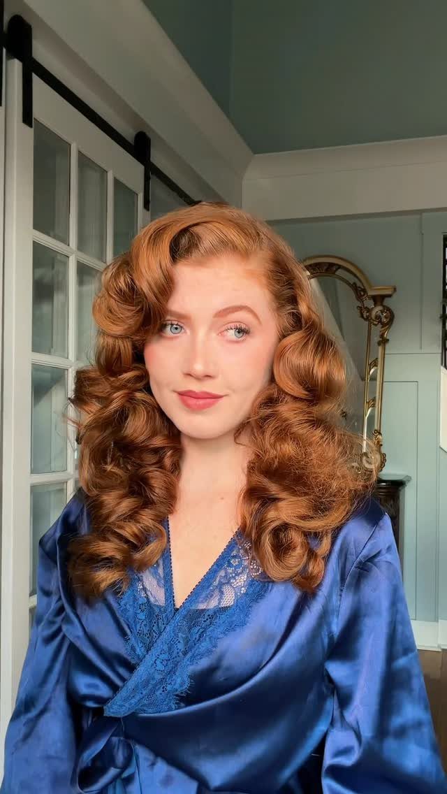 Woman in a blue satin robe wearing glossy, pinned-back copper waves