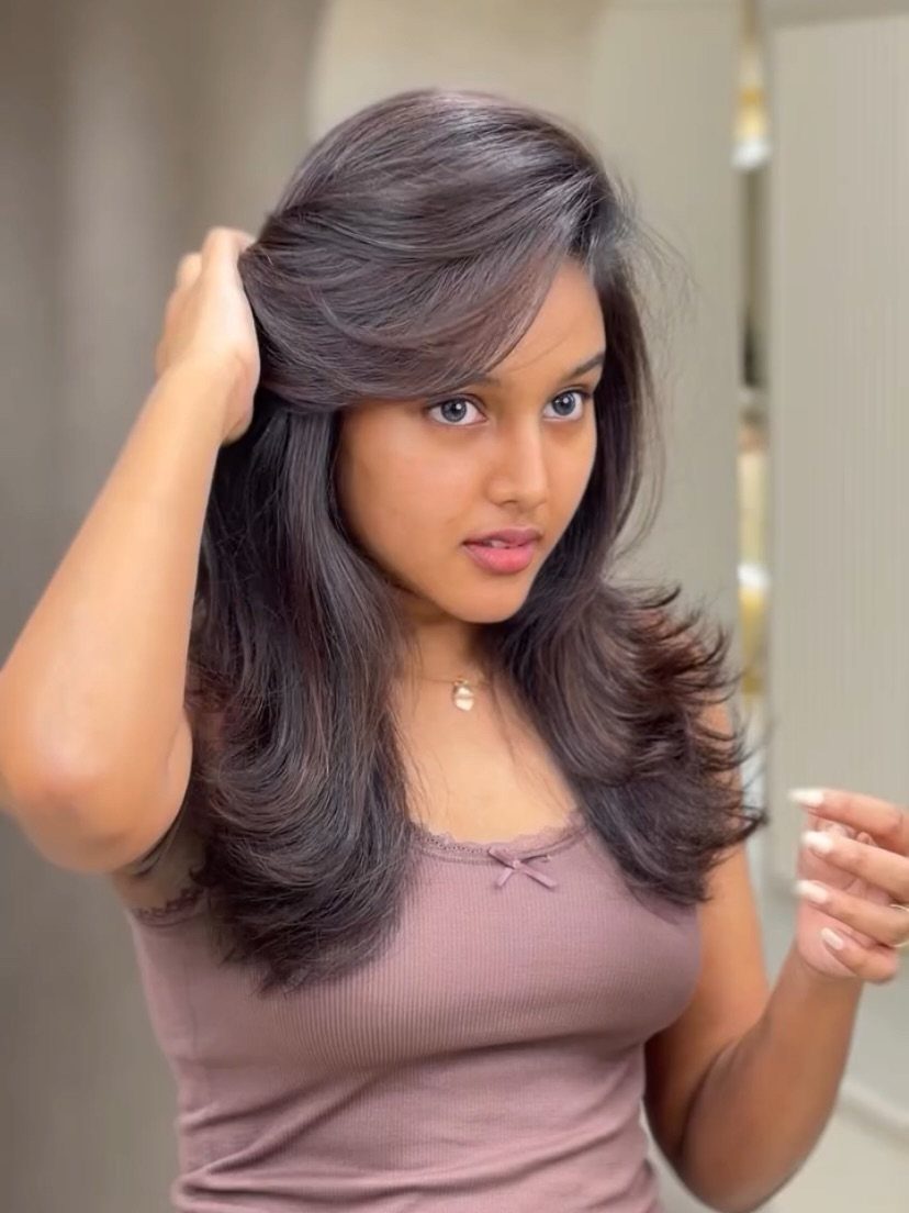 Woman with dark shoulder-length hair and softly curled, voluminous ends