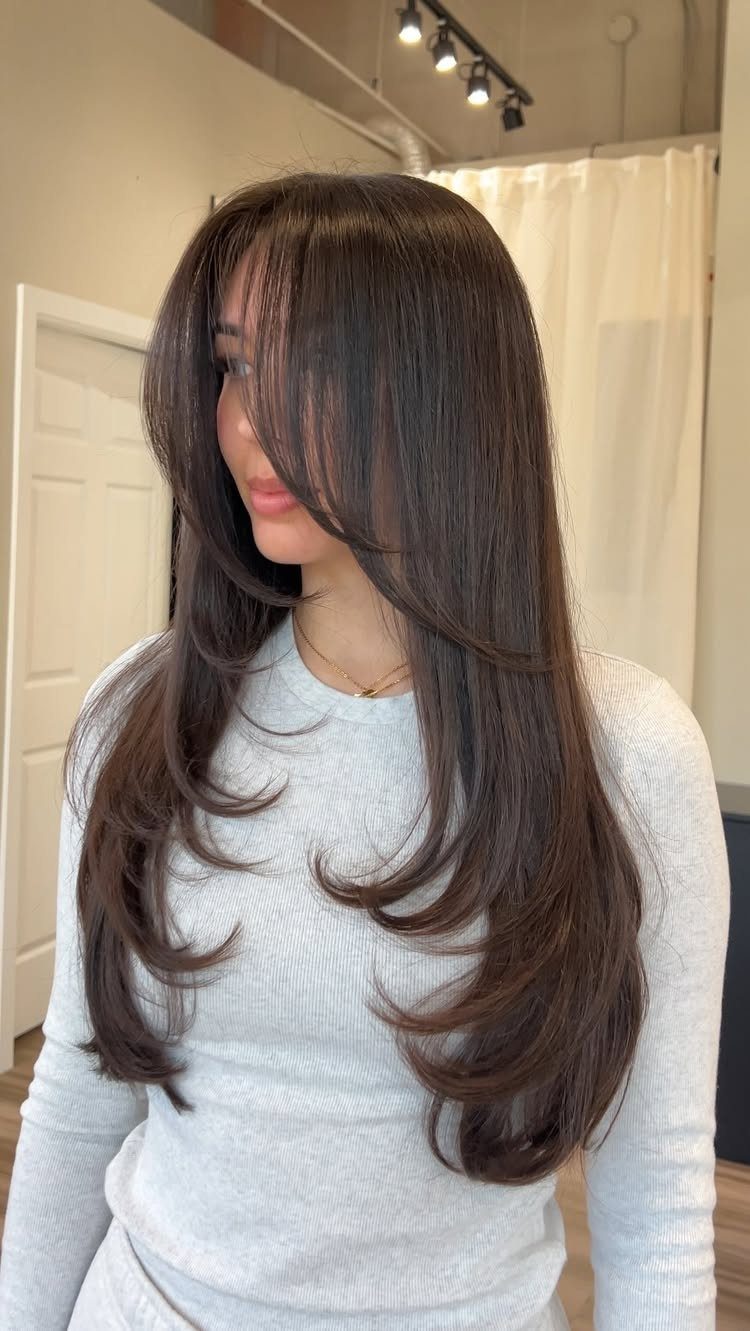 Woman showing long dark hair with chin-length angled front layers and curled ends