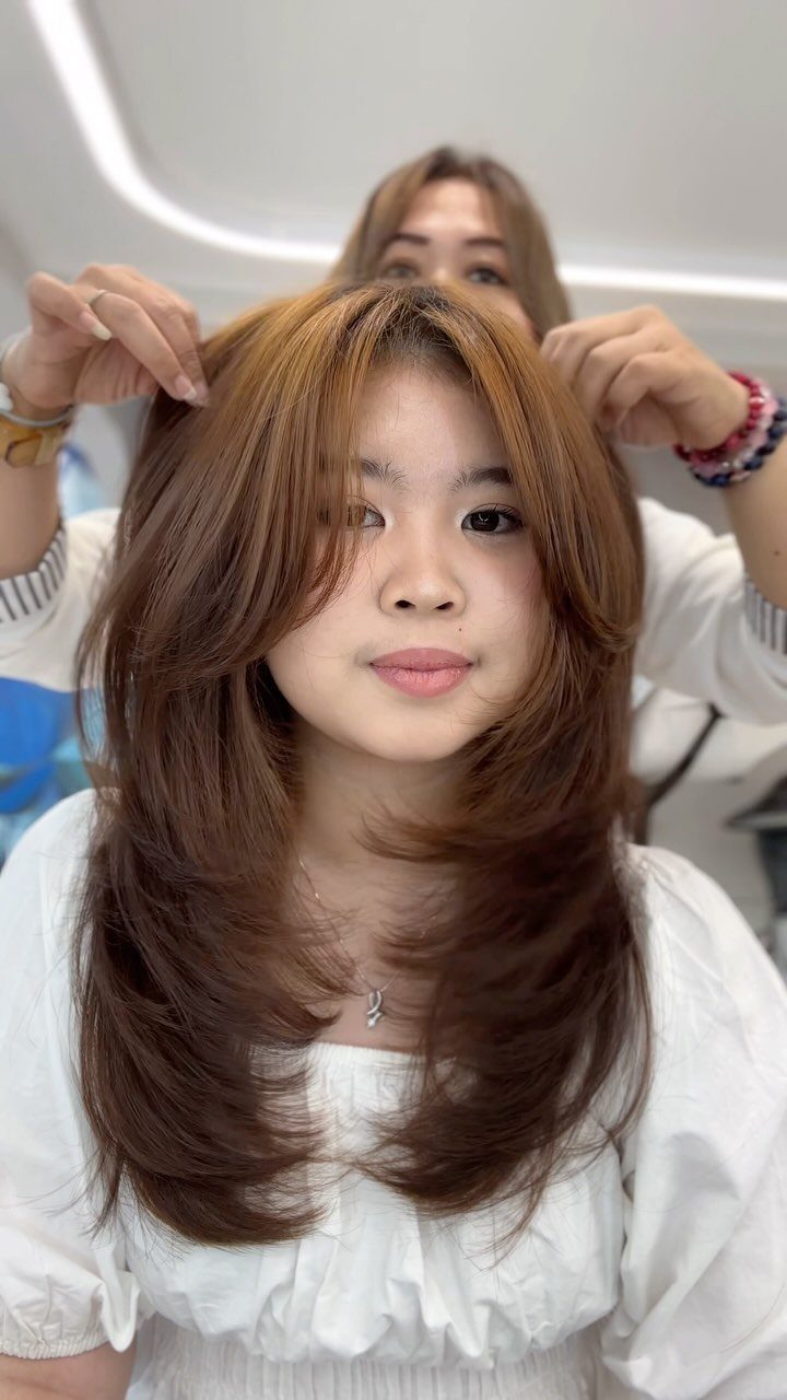 Long brown butterfly haircut with outward-sweeping face-framing layers