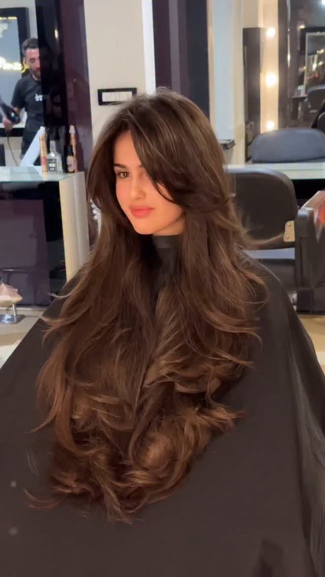 Woman displaying long dark layered hair with tousled, textured ends in a salon