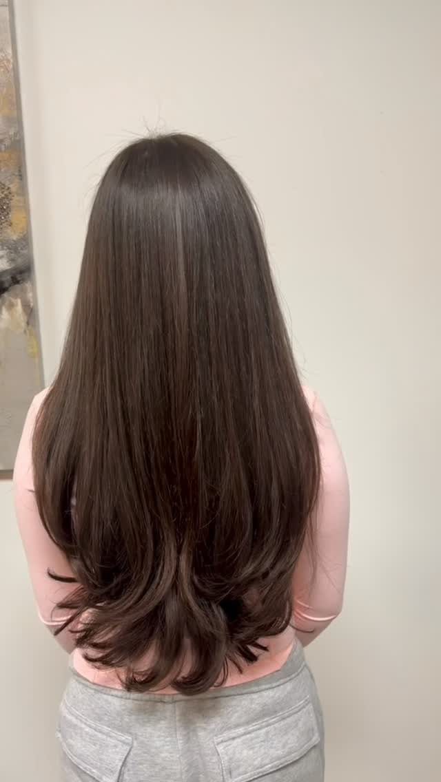 Long dark layered hair falls in a gently rounded U-shaped hemline