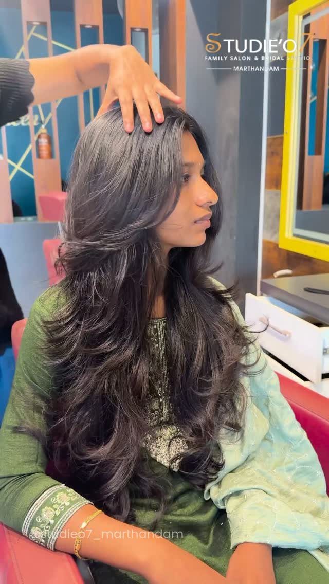 Woman with long dark hair styled in cascading, flowing layers in a salon