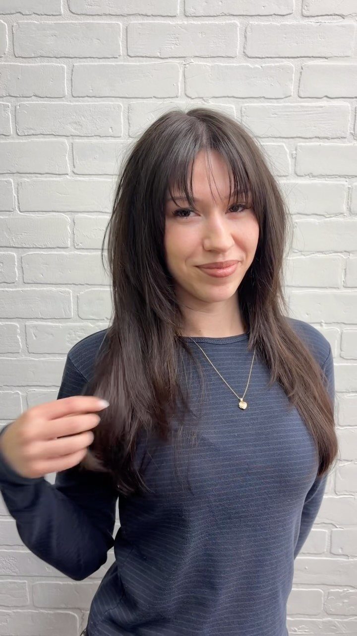 Woman showing long dark hair with airy wispy layers and soft bangs