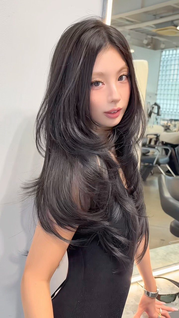 Woman showcasing long dark butterfly-cut layers with voluminous, flowing ends