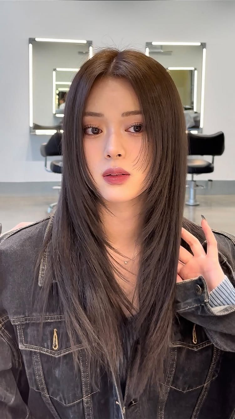 Long straight brown hair with soft feathered layers framing a woman's face
