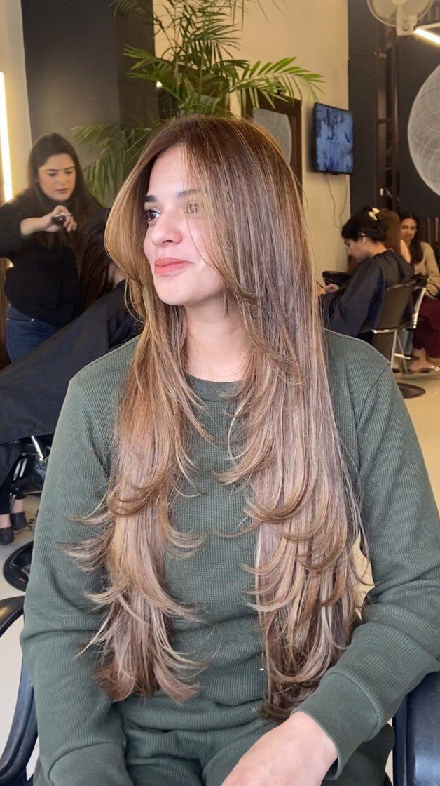 Woman with long highlighted hair and layered face-framing pieces seated in a salon
