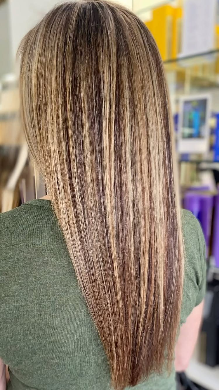 Straight brown hair with fine caramel highlights falls smoothly down the back