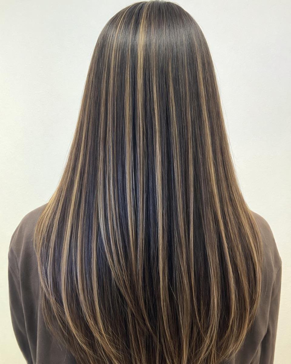 Long straight highlighted hair falls smoothly down the back of a person