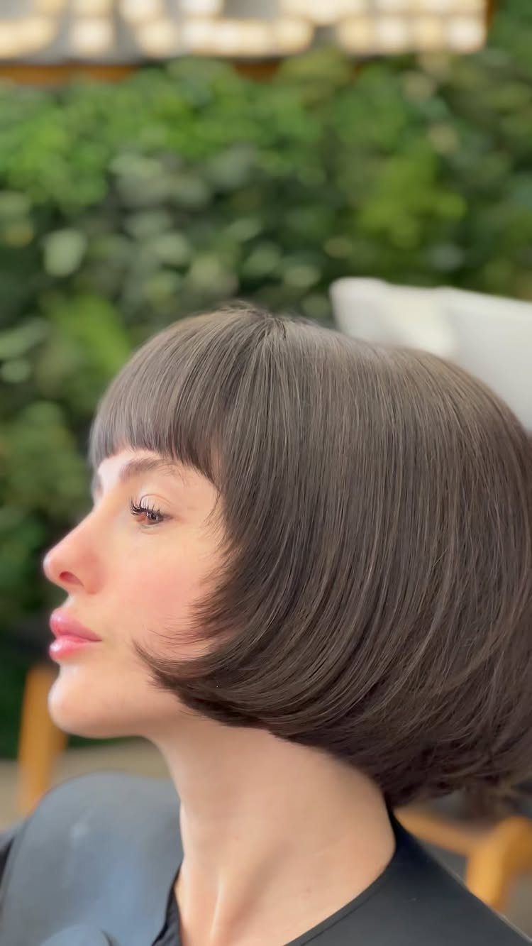 Dark brown bob with dense, straight-across bangs in side profile