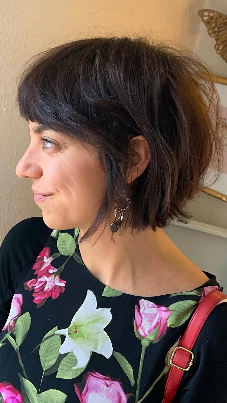 Woman with a dark chin-length bob, full fringe, and floral top