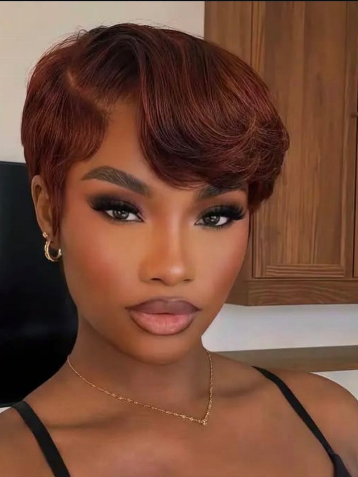Woman with a reddish-brown pixie cut and swept-forward fringe