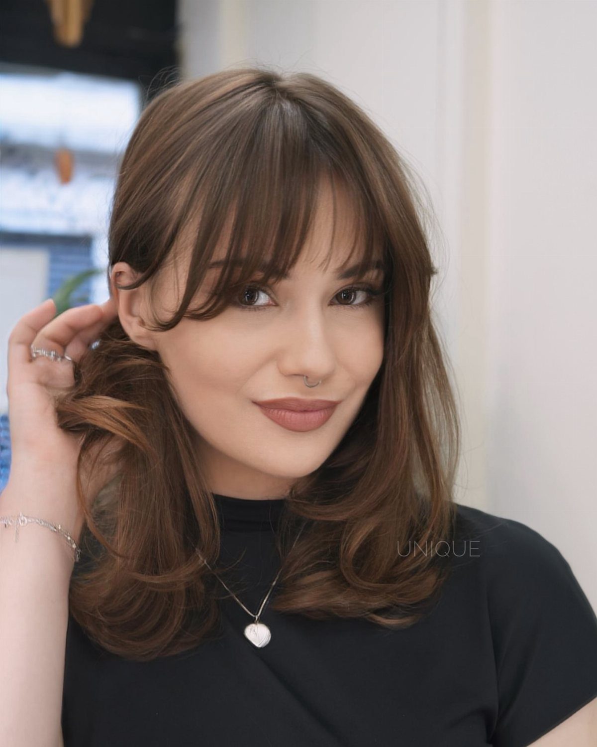 Woman with long brown hair and parted curtain bangs framing her face