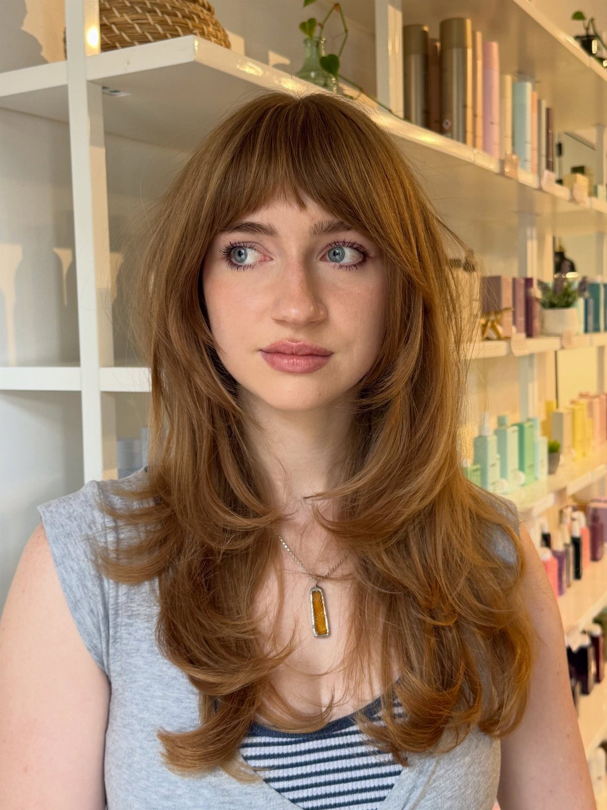 Woman with feathered, layered brown shag and straight bangs in a salon