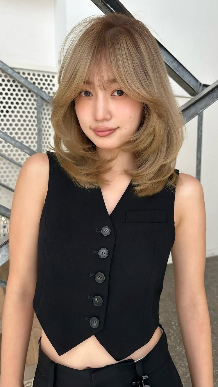 Woman with wispy layered bangs and shoulder-length, face-framing hair