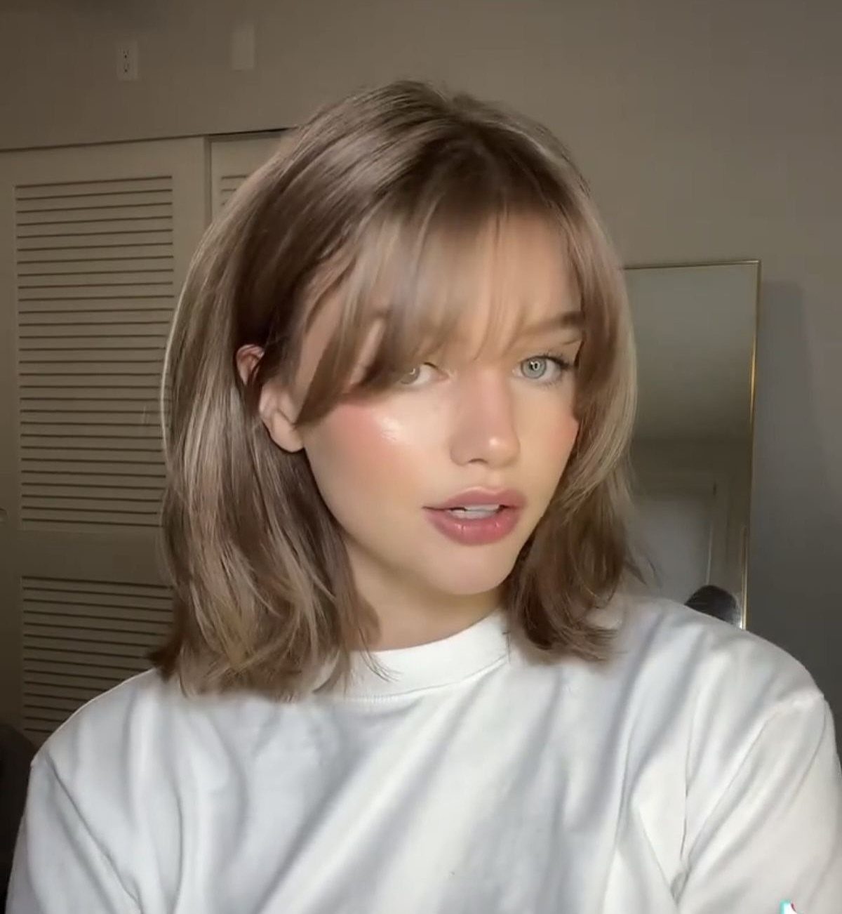 Woman with shoulder-length layered brown hair and wispy bangs