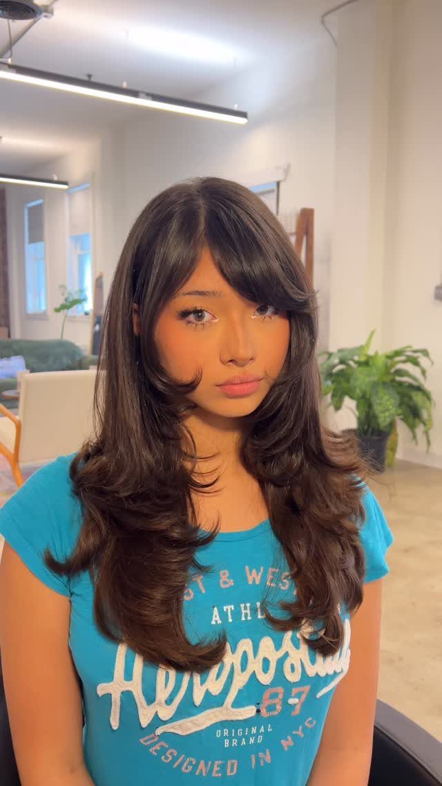 Woman showcasing long middle-parted side fringe blended into layered dark hair
