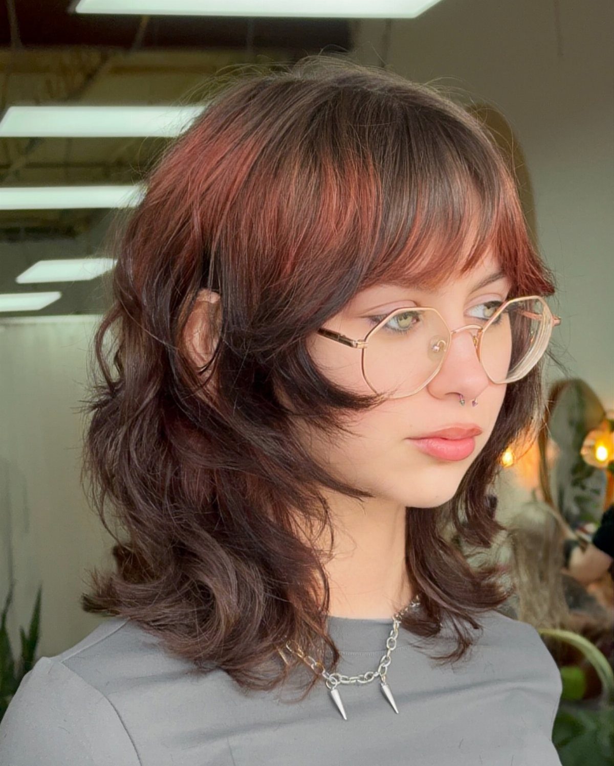Layered, tousled brown shag haircut with long bangs and reddish highlights
