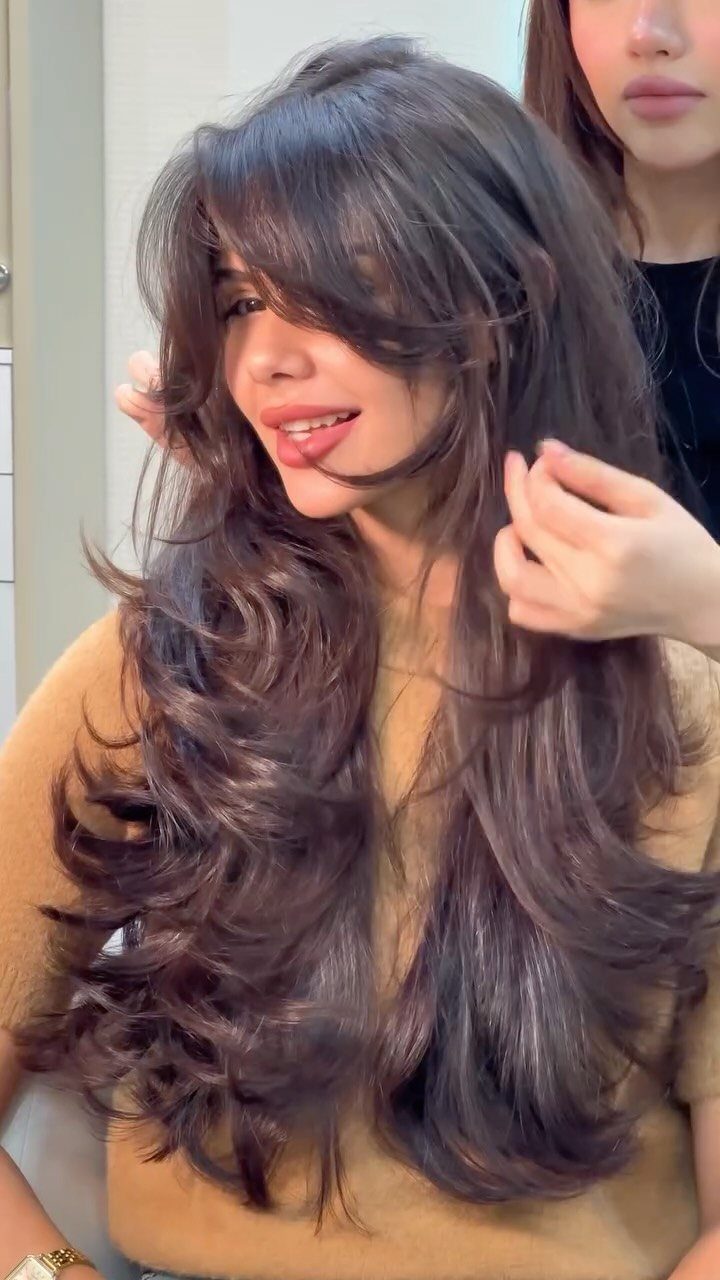 Woman showing long dark hair with center-parted face-framing curtain bangs